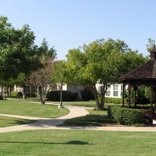 A peaceful park scene with a gazebo, surrounded by trees and well-maintained pathways.