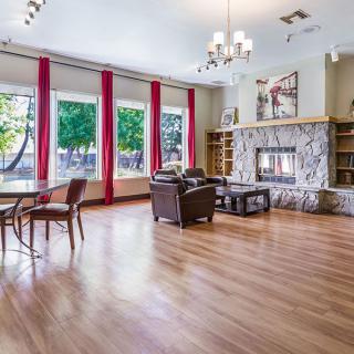 Spacious living room with large windows, a stone fireplace, and hardwood flooring.