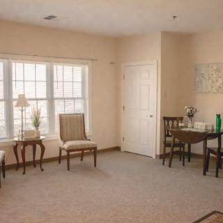 A cozy room with chairs, a table, and a large window allowing natural light.