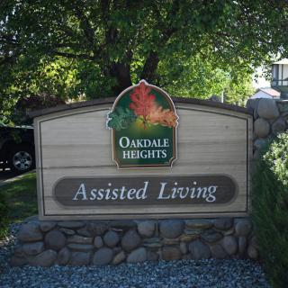 Sign for Oakdale Heights Assisted Living surrounded by trees and landscaping.