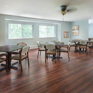 A bright and spacious dining room with wooden floors, tables, and chairs.