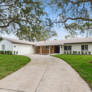 A single-story house with a curved driveway and well-maintained lawn.