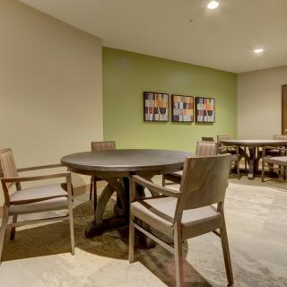 A modern room with a round table and chairs, featuring artwork on the wall.