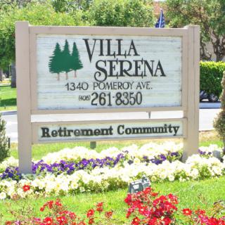 Sign for Villa Serena Retirement Community surrounded by flowers.