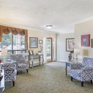 A cozy living room with patterned chairs, decor, and an open door leading outside.
