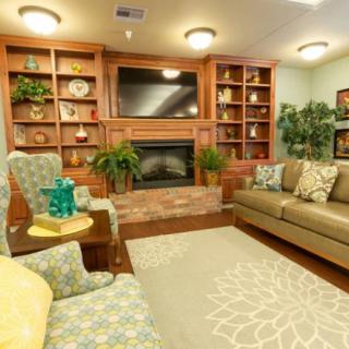 A cozy living room featuring a fireplace, sofa, and built-in shelves with decorative items.