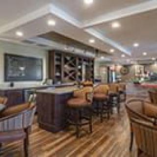 A stylish bar with seating and wine racks, featuring elegant interior design and wood flooring.