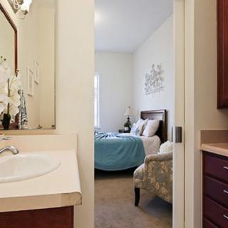 A view from the bathroom towards a cozy bedroom with a neatly made bed and simple decor.