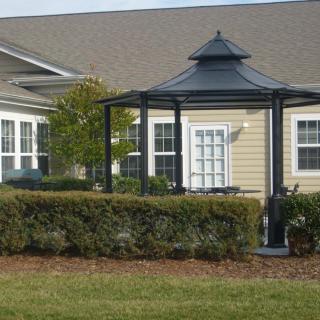 A well-maintained garden with a gazebo in front of a residential building.