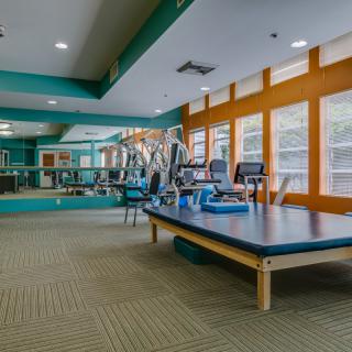 A spacious gym with exercise equipment and large windows.