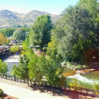 A scenic view of a river winding through a park with lush trees and mountains in the background.