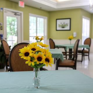 A cozy dining area adorned with a vase of sunflowers, creating a welcoming atmosphere.