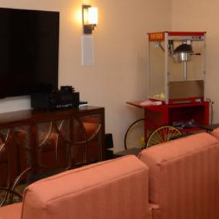 A cozy home theater setup with a large television, popcorn machine, and comfortable seating.