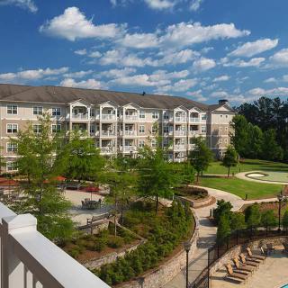 A scenic view of a residential apartment building surrounded by lush greenery and well-maintained pathways.