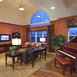 A modern living room with a piano, stylish furniture, and warm lighting.