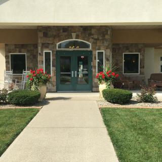 A building entrance with a pathway lined by plants and flowers.