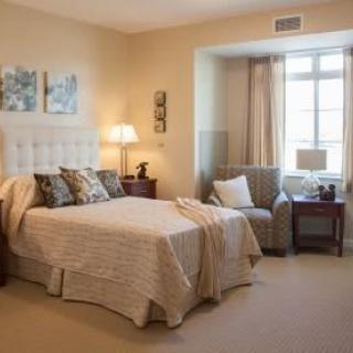 A cozy bedroom with a bed, armchair, and soft lighting.