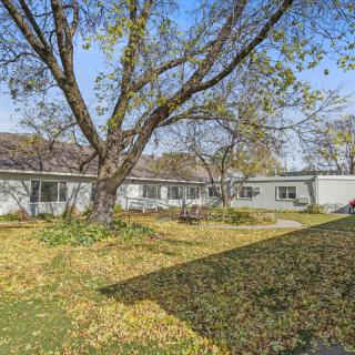 A single-story house surrounded by trees and fallen leaves on an autumn day.