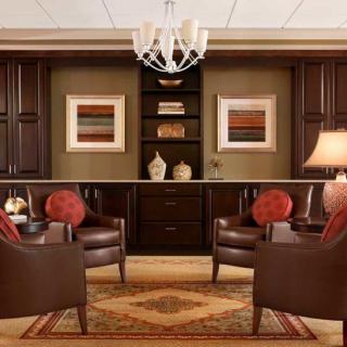 A cozy living room with dark wood built-in shelves, leather armchairs, and elegant decor.