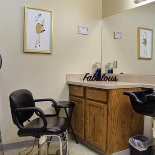 A quiet hair salon setup with chairs, a mirror, and decorative wall art.