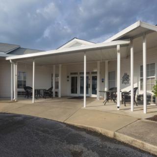A covered entrance of a building with pillars and outdoor seating.