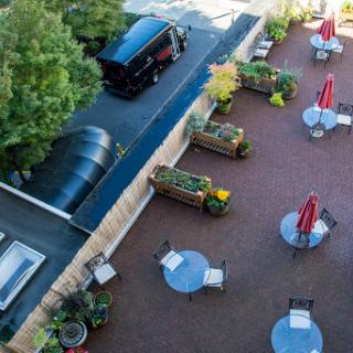 Aerial view of a cozy outdoor patio area with tables and plants, featuring a vehicle parked nearby.