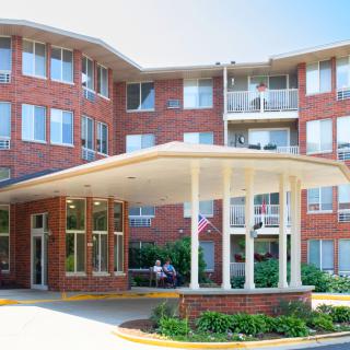 A brick residential building with a covered entrance and multiple balconies.