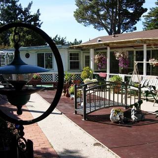 A charming house with a patio and garden, featuring a small decorative bridge and various plants.
