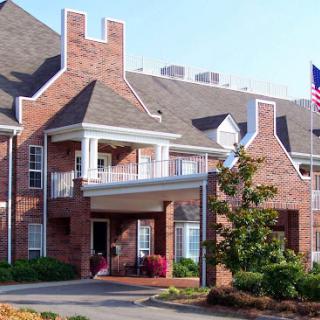A charming brick building showcasing a welcoming entrance, surrounded by greenery and featuring an American flag.