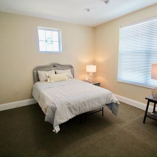 A minimalist bedroom with a bed, two lamps, and carpet flooring.