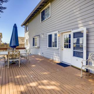 A sunny outdoor patio with a table and chairs under an umbrella on a wooden deck attached to a house.