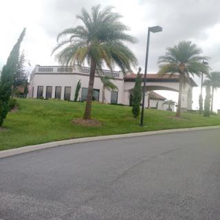 A picturesque view of a building surrounded by palm trees and lush landscaping under a cloudy sky.