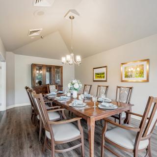 A well-furnished dining room featuring a large wooden dining table with chairs and a chandelier overhead.