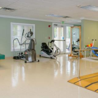 A spacious gym area equipped with various exercise machines and rehabilitation equipment.