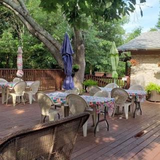 A charming outdoor patio with multiple tables, chairs, and colorful umbrellas set amidst a lush garden.