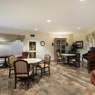 An inviting dining area with tables, chairs, and a piano on wood flooring.