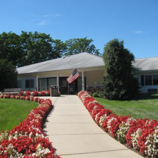 A well-maintained building with a pathway lined by colorful flowers and an American flag flying at the entrance.