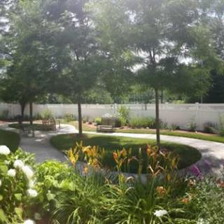 A serene garden with a winding pathway surrounded by trees and colorful flowers.