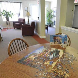 A cozy living room area with a table, chairs, and a partially completed puzzle.
