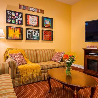 A cozy living room with a striped sofa, wooden coffee table, and colorful artwork on the wall.