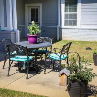 A cozy patio setup with a table and chairs, surrounded by potted plants in a backyard setting.