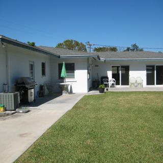 A residential backyard with a lawn and patio area.