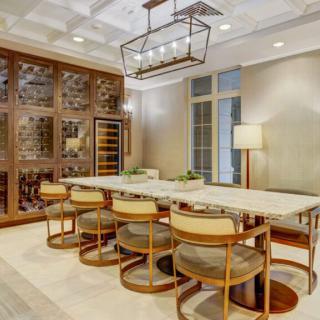 A luxurious modern dining room featuring a marble table, stylish chairs, and an elegant wine rack.
