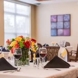 A beautifully set dining table with wine glasses and a colorful flower centerpiece in an elegant restaurant setting.