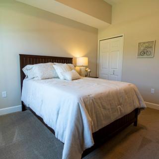 A cozy bedroom with a neatly made bed and warm lighting.