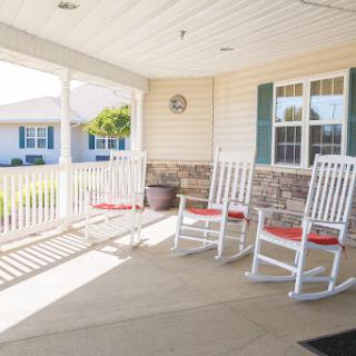 A cozy porch featuring white rocking chairs, perfect for enjoying a sunny day.