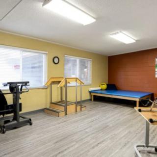 A physical therapy room equipped with a small staircase, exercise equipment, and a therapy bed.