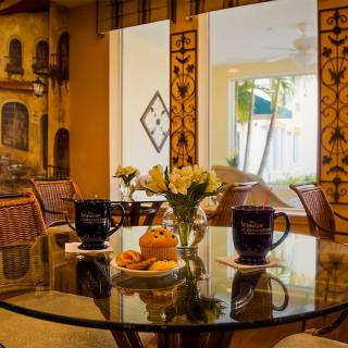 Cozy dining area with a glass table, adorned with flowers and coffee mugs.