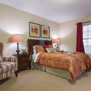 A cozy bedroom interior with a bed, side tables, and lamps.