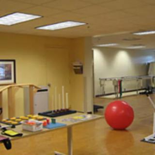 A physical therapy room equipped with exercise tools and a large red fitness ball.